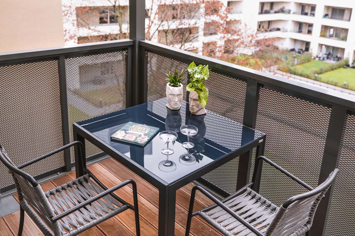 Balkon mit Tisch und 2 Stühlen, Blick in einen Innenhof